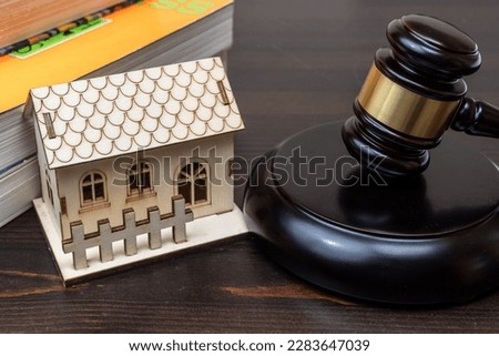 A stern judge, gavel in hand, stands before a wooden table in a courtroom. Justice is being served as an eviction due to unpaid mortgage law is considered. Royalty-Free Stock Photo #2283647039