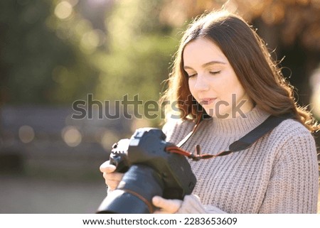 Serious photographer checking photos on dslr camera in a park