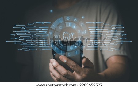 People hand using smartphone or computer laptop to access smart home application from internet wireless connection to control and monitoring smart device inside of the house. Internet of things. Royalty-Free Stock Photo #2283659527