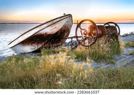 Rowing boat on slipway with hoist mechanism along the dyke of the IJsselmeer with red colored rain clouds drifting over the lake