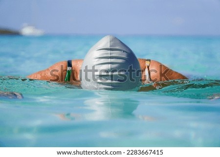 female swimmer in a gray cap swimming in the island turquoise sea water. Women's sport in summer Royalty-Free Stock Photo #2283667415
