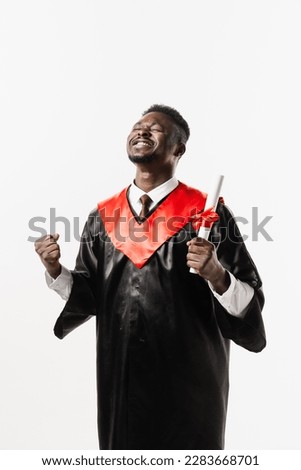 Graduate african man is graduating college and celebrating academic achievement. Happy african student in black graduation gown and cap raises masters degree diploma above head on white background Royalty-Free Stock Photo #2283668701