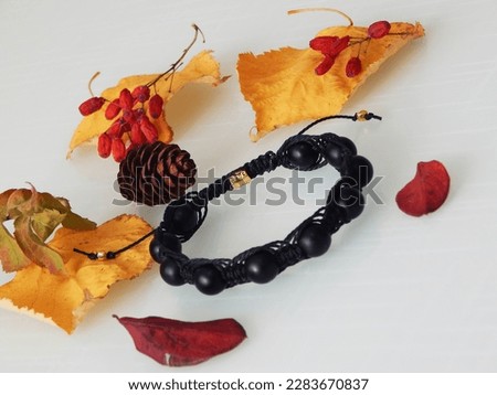 Hippie black bracelet on a white. Black bracelet and yellow leafs