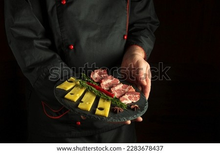 Professional chef holding a serving plate with a ham and cheese appetizer. The concept of serving food by a waiter in a restaurant. Free space for recipe or menu