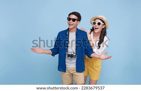 Happy smiling Asian couple tourist traveler standing hugging and looking copy space isolated on blue background. Vacation time