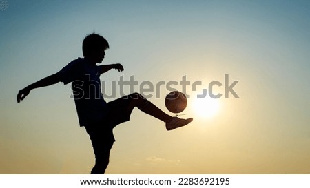 Silhouette action sport outdoors of football player on the sunset sky. Picture with copy space of athlete man kicking soccer ball.