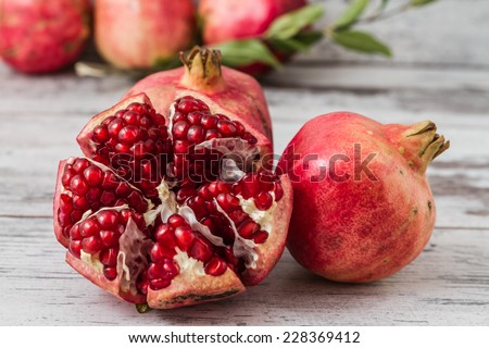 Half pomegranate and raw pomegranates on a white wooden background Royalty-Free Stock Photo #228369412