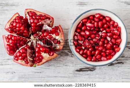 Half pomegranate and pomegranate seeds on a white wooden background Royalty-Free Stock Photo #228369415