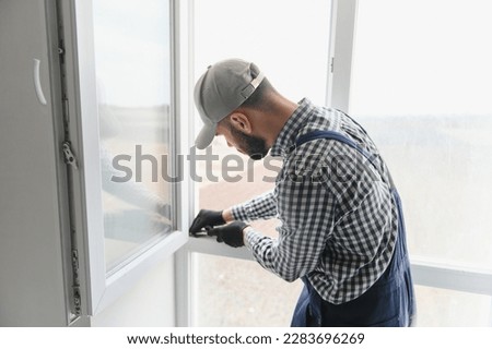 Worker installing plastic window indoors. Royalty-Free Stock Photo #2283696269