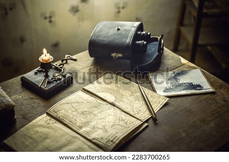 Ship's map on a wooden table with burning candles.Still life in the marine style. Marine attributes in the captain's room.Pirate treasures.