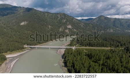Bridge over the river Katun. Summer landscape from above. Bridge across the river from a height. Bridge between the mountains across the river. Photographs of the Republic of Gorny Altai in summer
