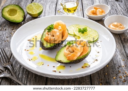 Avocado with fried prawns on and cocktail sauce on wooden background  Royalty-Free Stock Photo #2283727777
