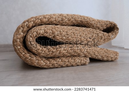 Wicker woven carpet, folded modern natural braided woven wicker carpet on the parquet in the bedroom. Wicker carpet concept idea photo. Eco-friendly interior detail in home. Royalty-Free Stock Photo #2283741471