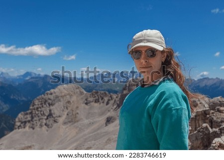 Portrait of one young woman in sunglasses who is hiking outdoors in dolomite mountains, Latemar, Trentino, Italy. Traveling photography and outdoor sport activity concept