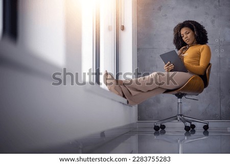 Portrait of female designer working in modern office.Serious african-american businesswoman using digital tablet in office.