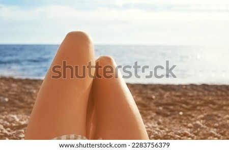 Women's feet on the beach at sunset against the background of the sea and sky, soft selective focus. Vacation background