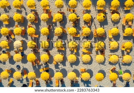Aerial view of yellow umbrellas on sandy beach at sunset in summer in Sardinia, Italy. Tropical colorful landscape. Travel and vacation background. Top down view from drone. Tropical pattern. Concept Royalty-Free Stock Photo #2283763343