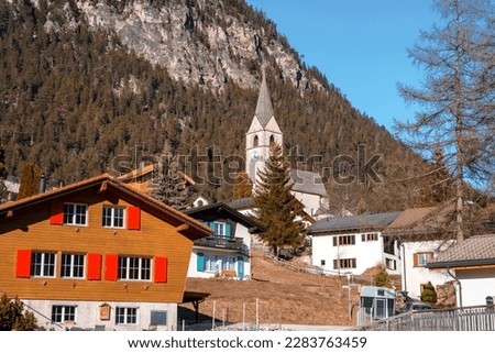 Beautiful church and houses with majestic mountain in background at Swiss Alps. Winter holiday travel concept
