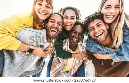 Multiracial young people smiling at camera outside - Group of best friends having fun hanging out together on summer day - Life style concept with guys and girls laughing out loud