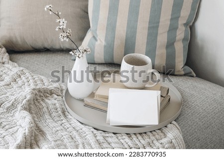 Spring birthday greeting card, wedding invitation. Easter breakfast still life. Blank greeting card mockup. Cup of coffee, tea on books. Blossoming cherry plum tree branches in little glass vase.