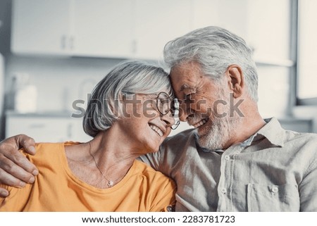 Happy mature husband and wife sit rest on couch at home hugging and cuddling, show care affection, smiling senior loving couple relax on sofa have fun, enjoy tender romantic family weekend together