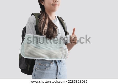Travel insurance concepts. Young woman with hand injured wearing splint, broken arm, wearing backpack, showing thumb up, smiling face, isolated on white background