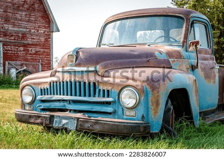 A classic half ton pickup truck in front of a red barn on the Saskatchewan prairies Royalty-Free Stock Photo #2283826007