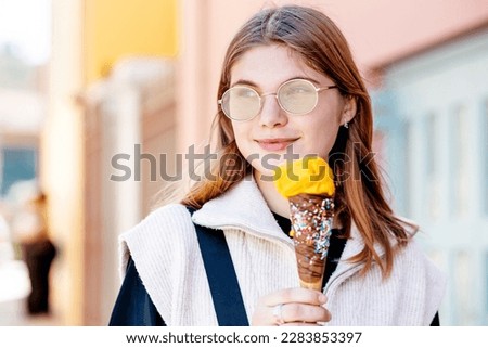 Outdoor closeup fashion portrait of young hipster crazy girl eating ice cream in summer hot weather in round mirror sunglasses have fun and good mood. Toned style instagram filters.