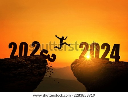 Man jumping on cliff 2024 over the precipice with stones at amazing sunset. New Year's concept. 2023 falls into the abyss. Welcome 2024. People enters the year 2024, creative idea. Royalty-Free Stock Photo #2283853919