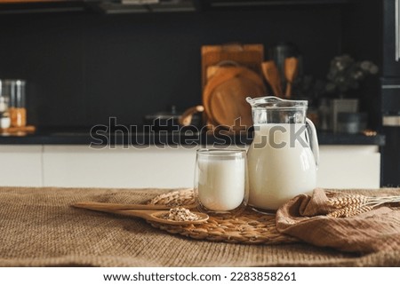 Milk in a jug and a glass, a wooden spoon with oatmeal and ears of wheat on the table. Royalty-Free Stock Photo #2283858261