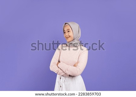 Photo of young smiling confident  asian moslem woman in  hijab hold hands crossed folded isolated on purple background studio portrait. 