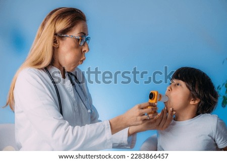 Pediatric pulmonologist measuring lung capacity and force expiratory volume of a boy, spirometer. Pediatric pulmonology, medical discipline specialized in the diagnosis and treatment of diseases   Royalty-Free Stock Photo #2283866457