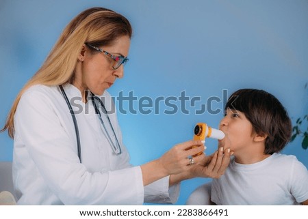 Pediatric pulmonologist helping little boy with aero inhaler. Pulmonologist, medical doctor who specializes in the diagnosis and treatment of diseases and disorders of respiratory system     Royalty-Free Stock Photo #2283866491