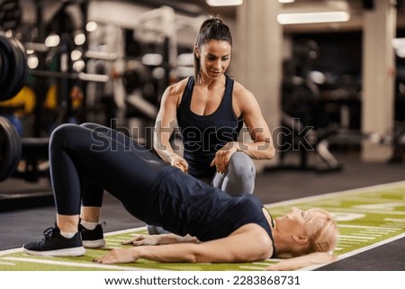 A cheerful coach is training sportswoman in a gym. Royalty-Free Stock Photo #2283868731