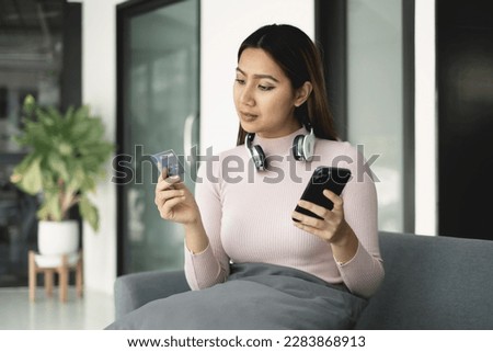 Asian girl shopping online holding credit and using smartphone enter their card number in the mobile phone app to purchase and payment in internet store.