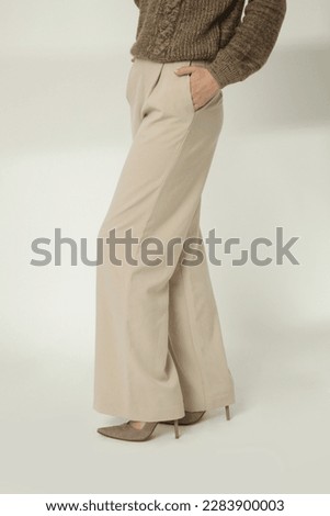Female model wearing beige smart casual high rise wide leg trousers with high heels. Studio shot. Royalty-Free Stock Photo #2283900003