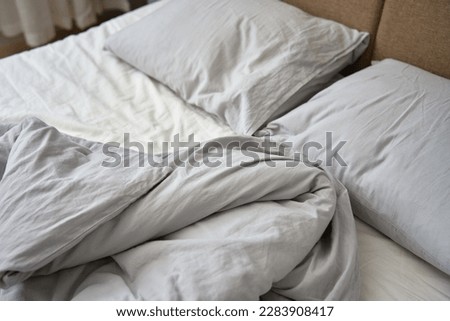 Unmade bed after sleeping. Crumpled bed with pillows, blanket and crumpled sheets in bedroom. Morning housekeeping Royalty-Free Stock Photo #2283908417