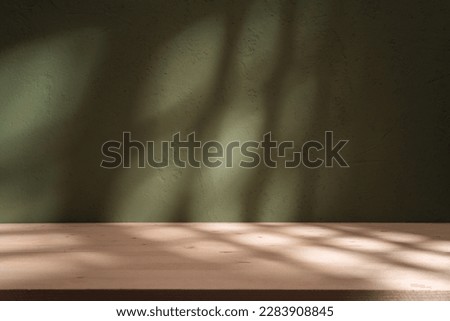 Empty table on khaki green texture wall background. Composition with monstera leaves shadow on the wall and light reflections. Mock up for presentation, branding products, cosmetics food or jewelry. Royalty-Free Stock Photo #2283908845