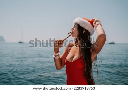 Woman travel sea. Happy tourist enjoy taking picture on the beach for memories. Woman traveler in Santa hat looks at camera on the sea bay, sharing travel adventure journey