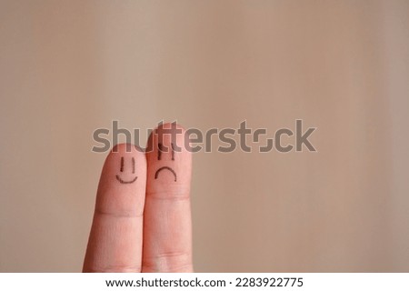 Two faces on fingers, couple of happy and unhappy mood, concept of negative or positive, expression