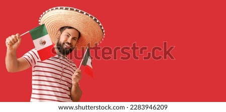 Handsome man in Sombrero and with Mexican flags on red background with space for text Royalty-Free Stock Photo #2283946209