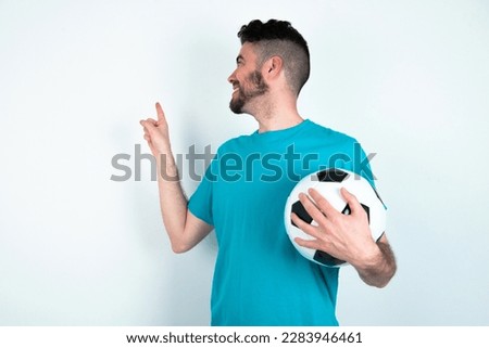 young handsome man wearing blue T-shirt over white background smile excited directing fingers look empty space