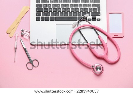 Stethoscope, laptop, badge and drugs on pink background