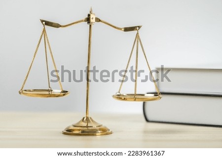 Shiny golden balanced scale and law book on desk in law school as concept justice and legal symbol. Scale balance for righteous and equality judgment by lawyer and attorney. equility