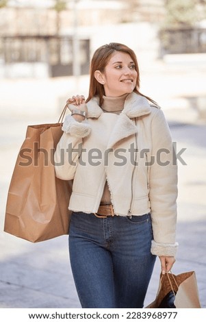Stylish woman walking outdoors with shopping bags. Shopping concept.