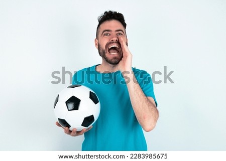young handsome man wearing blue T-shirt over white background shouting excited to front.