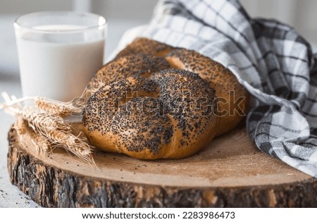 Classic wheat braid with poppy seeds. Delicious bread close-up. Freshly baked sourdough bread with a golden crust on a wooden board. The context of a bakery with delicious bread. 