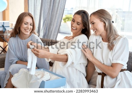 Caucasian pregnant woman opening gifts from friends 