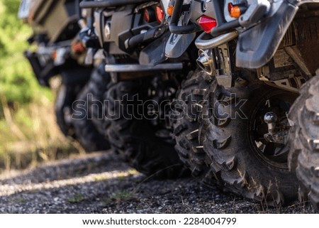 Close-up tail view of ATV quad bike on dirt country road. Dirty wheel of AWD all-terrain vehicle. Travel and adventure concept.