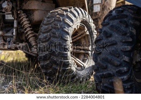 Close-up tail view of ATV quad bike on dirt country road. Dirty wheel of AWD all-terrain vehicle. Travel and adventure concept.